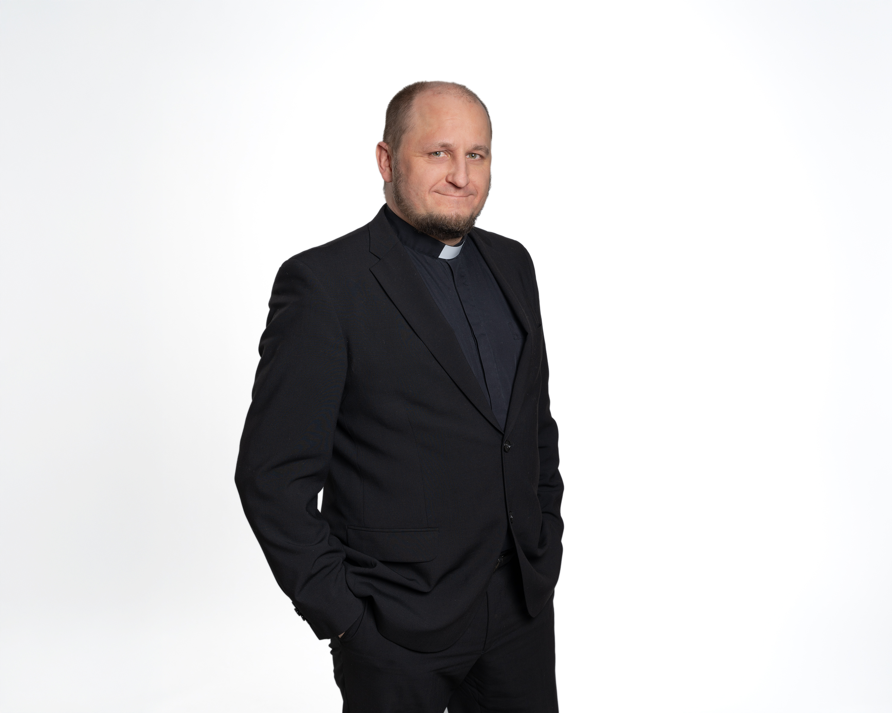 Kirkkoherra Olli Viitaniemi tummassa puvussa kädet taskussa seisoen.